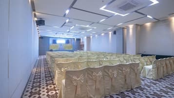A conference room with rows of tables and chairs, a patterned carpet, and a modern ceiling design.