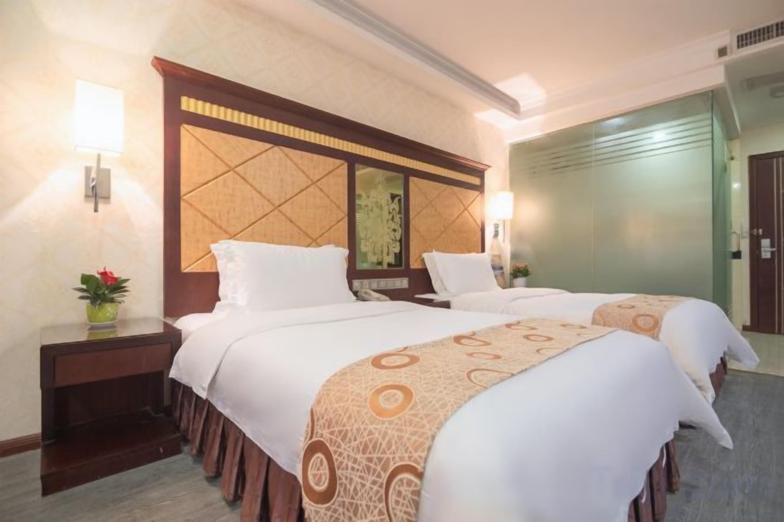 Une chambre d’hôtel avec deux lits, une table de chevet, un miroir et un luminaire fixé au mur.