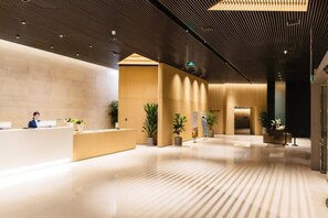 A spacious lobby with a reception desk, potted plants, and a modern ceiling design. - A Naya Anlan Hotel (Qinhuangdao)