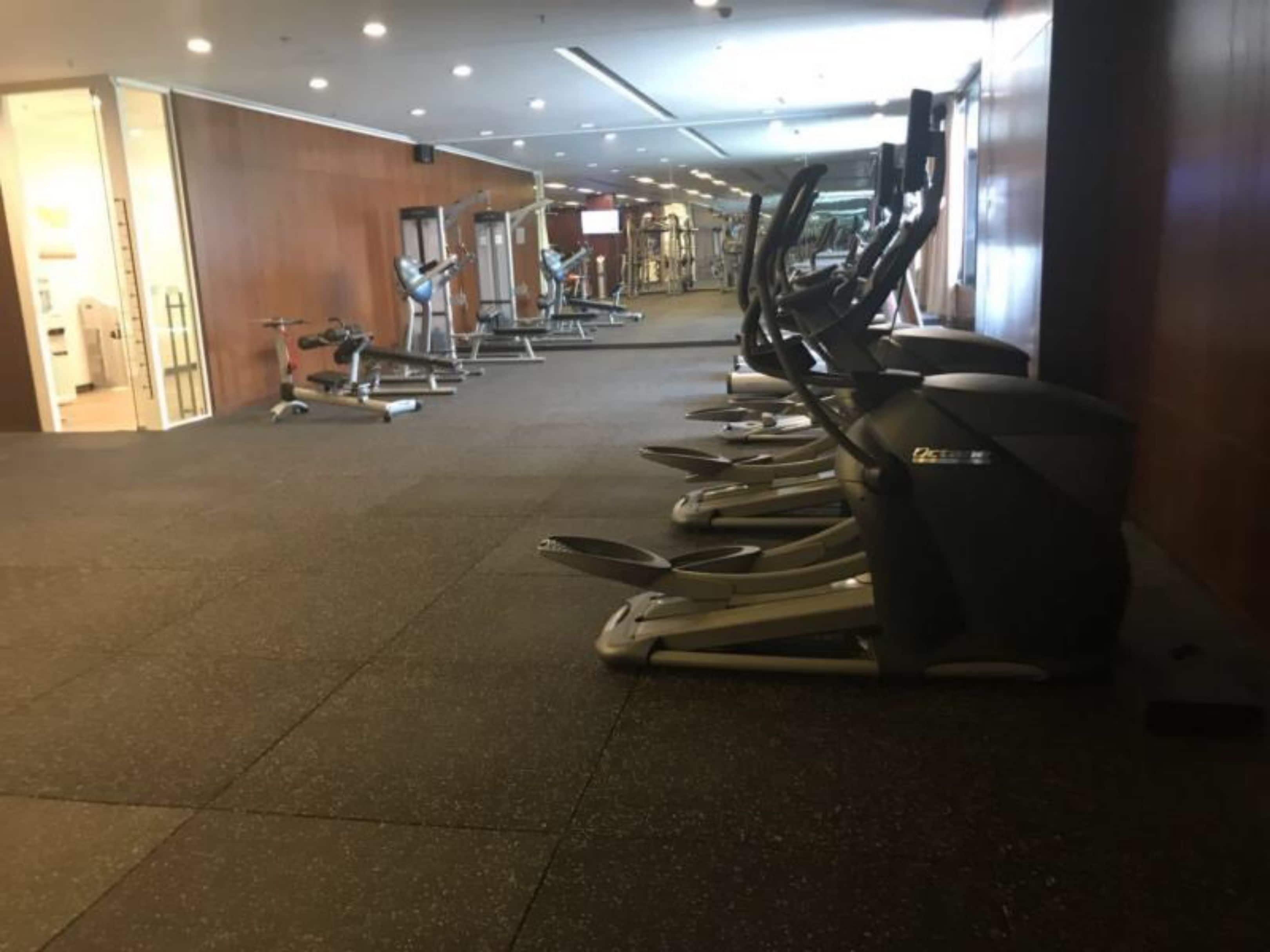 A gym with treadmills lined up against the wall, a weight machine, and a mirror.