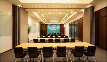 A conference room with a long table and chairs, a large screen at the front, and a modern ceiling design.