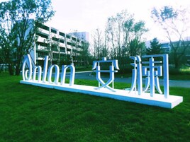 A sign with Chinese characters in a park-like setting with grass and trees.