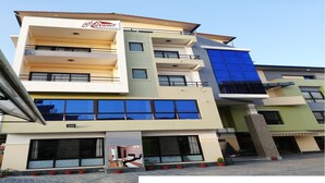 Un hotel de varios pisos con balcones, ventanas amplias y un letrero que indica que es un hotel.
