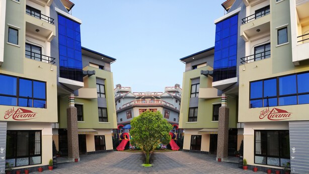 Un hotel con un patio central, varios balcones y una zona de juegos infantiles con toboganes.