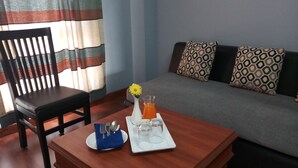 Una mesa de comedor con una bandeja dispuesta, un florero con una flor y un vaso de jugo de naranja.