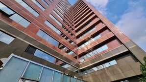 Un edificio moderno de gran altura con fachada enrejada y numerosas ventanas.
