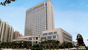 Un hotel moderno con una torre destacada y una estatua en su fachada.