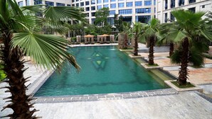 Una piscina rodeada de palmeras y un edificio moderno al fondo.