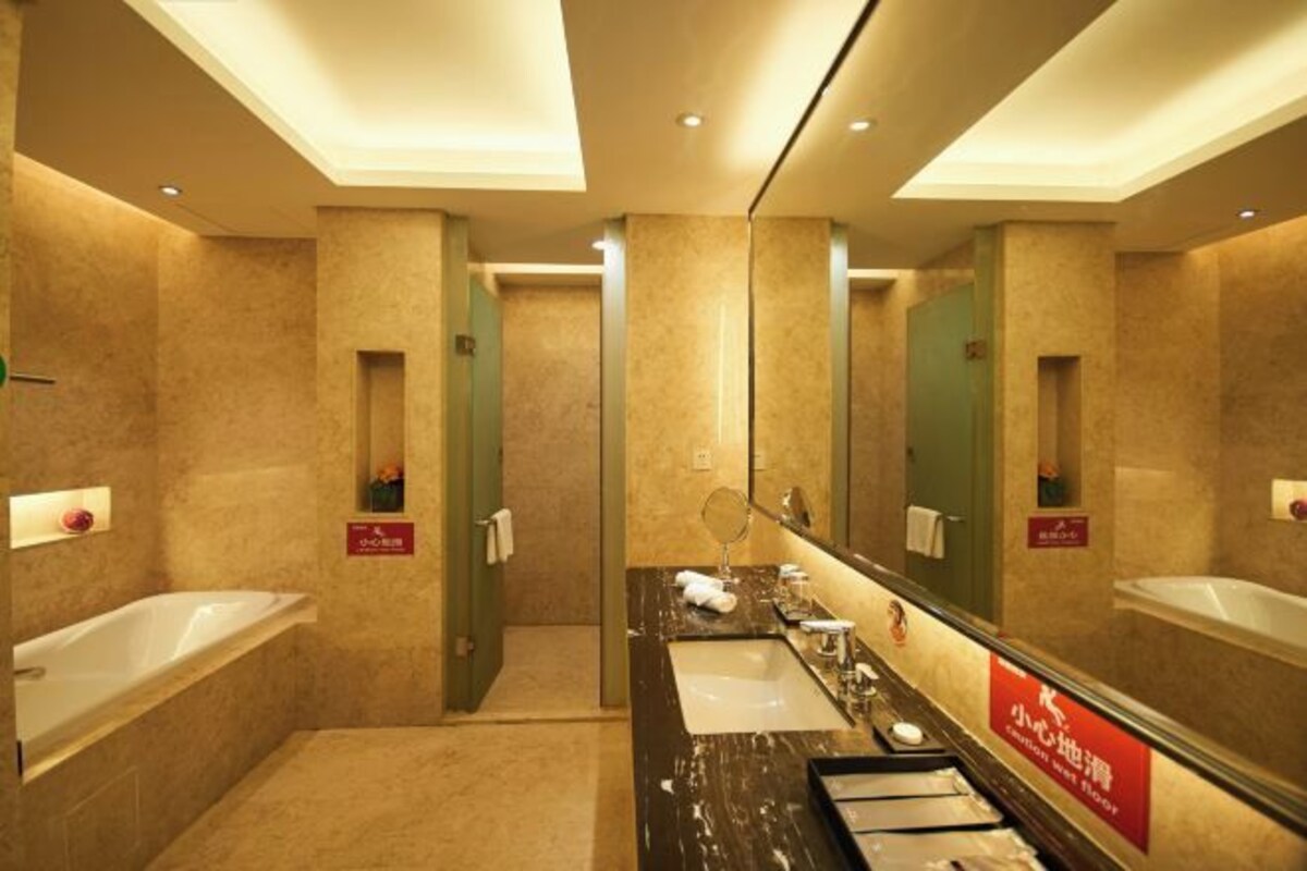 A hotel bathroom with a bathtub, a sink, a mirror, and a shower.