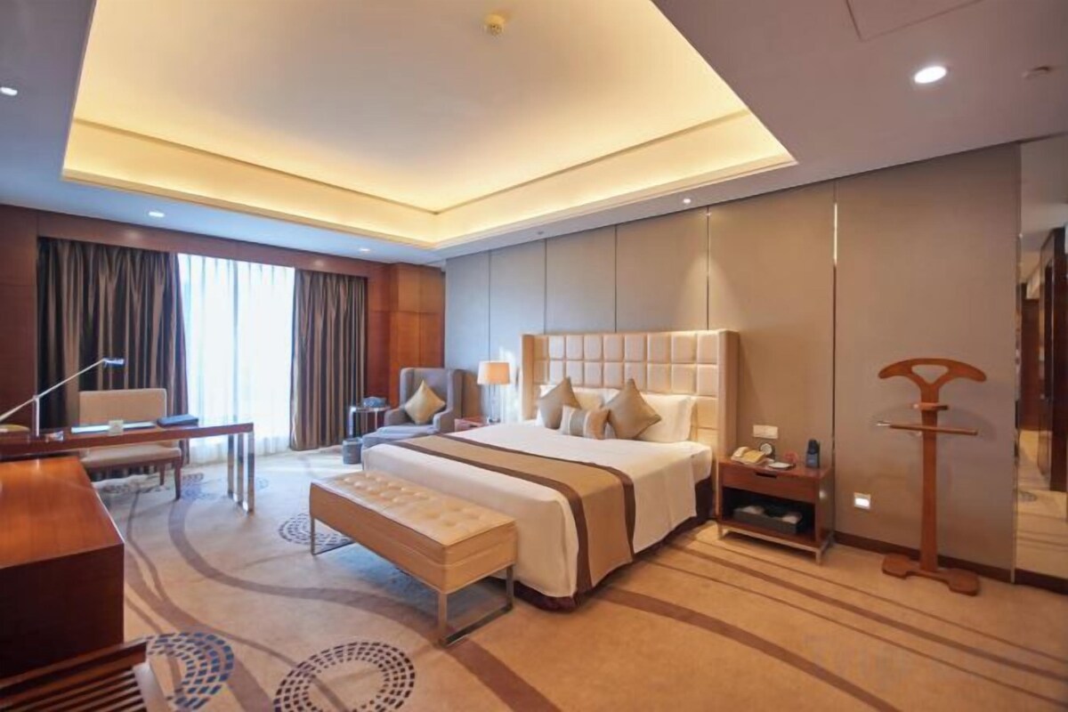 Una habitación de hotel moderna con una cama grande, un escritorio y una zona de estar.