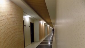 Un long couloir étroit, doté d’un sol carrelé noir et blanc poli, de lambris en bois sur les murs et de portes disposées à intervalles réguliers.