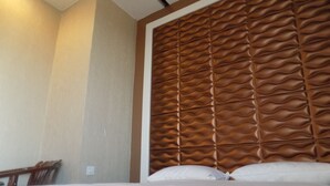 Une chambre d’hôtel avec un grand lit, une tête de lit en bois et un mur sobre.