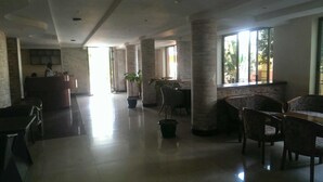 A spacious lobby with a reception desk, seating area, and large windows providing natural light. - Makutano Hotel (Kampala)