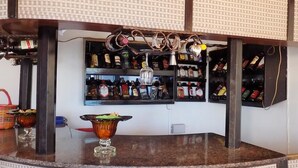 A bar area with shelves of liquor bottles, a bar counter, and a decorative light fixture. - Star Royal Motel (Kampala)