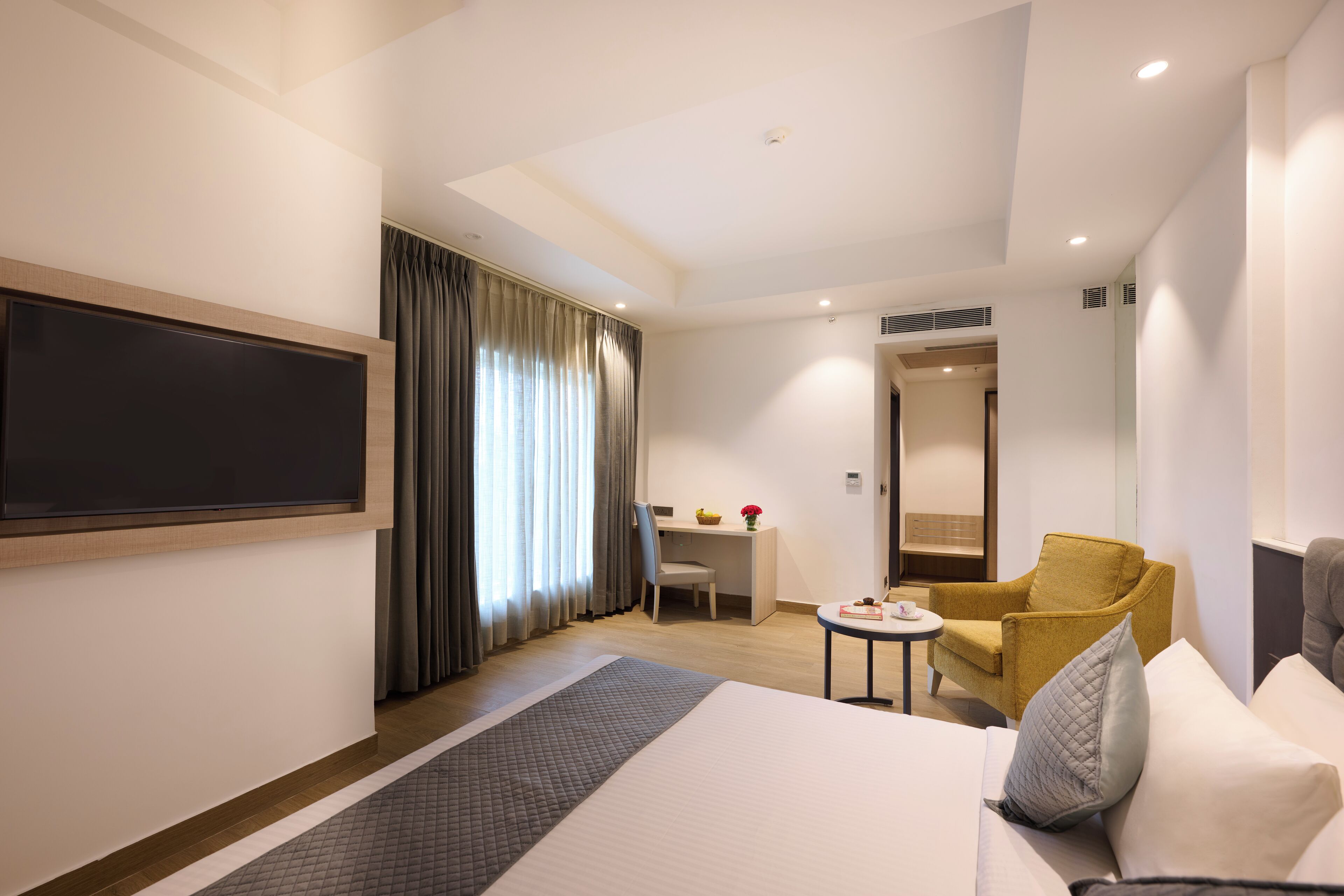 A hotel room with a bed, a desk, a chair, a TV, and a bathroom.
