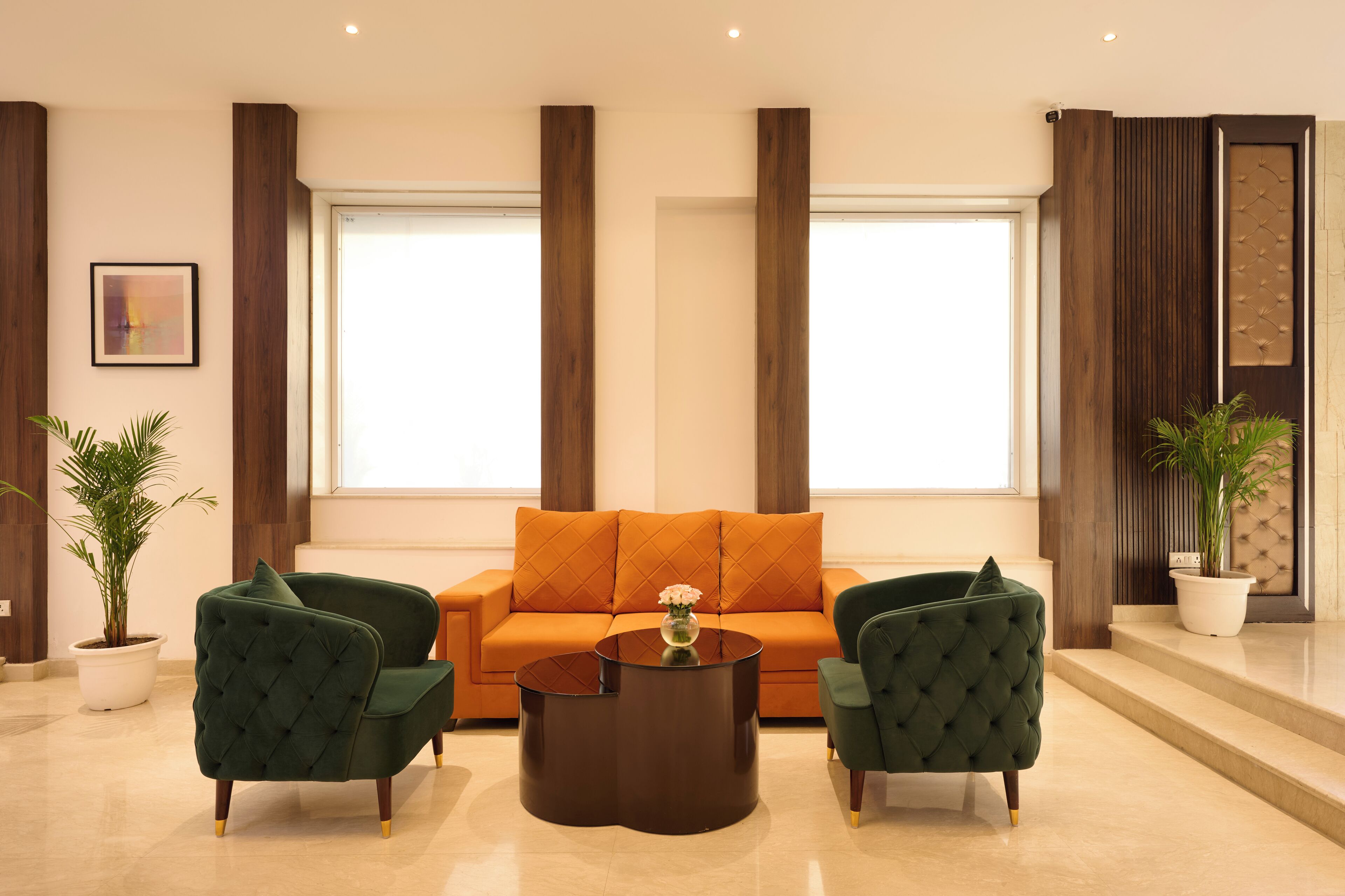 A modern living room with a sofa, two armchairs, a coffee table, and potted plants.