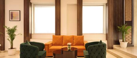 A modern living room with a sofa, two armchairs, a coffee table, and potted plants.