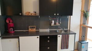 Une cuisine compacte équipée d’un réfrigérateur, d’une machine à café, d’un évier et d’un petit placard.