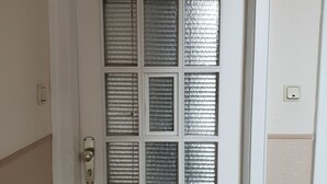 Une porte blanche ornée d’une grille de panneaux en verre dépoli et dotée d’une poignée en laiton.
