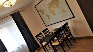 Un coin repas avec une table et des chaises en bois, une carte du monde accrochée au mur et une fenêtre avec des rideaux.
