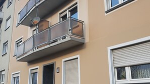 Un immeuble résidentiel à plusieurs étages, doté de balcons, d’une porte et de fenêtres.