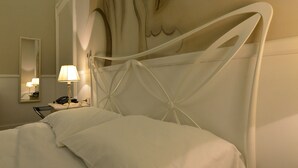 A hotel room with a bed, a bedside table with a lamp, a mirror, and a decorative wall mural. - Conte di cavour (Foggia)