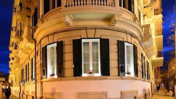 A historic building with a curved facade, large windows with shutters, and a balcony with balustrades. - Conte di cavour (Foggia)