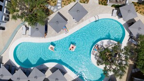 An aerial view of a swimming pool with a unique wavy design, surrounded by lounge chairs and umbrellas. - Philoxenia Hotel (Polygyros)