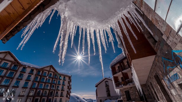 A hotel with a wooden balcony and icicles hanging from the ceiling.