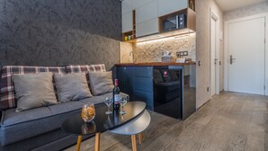 A modern living room with a sofa, a coffee table, and a kitchen area with cabinets and a countertop.