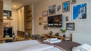 A hotel room with a bed, a TV, a desk, and a bookshelf.