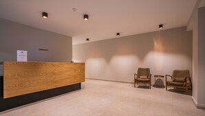 A reception area with a wooden reception desk, two armchairs, and a small side table.