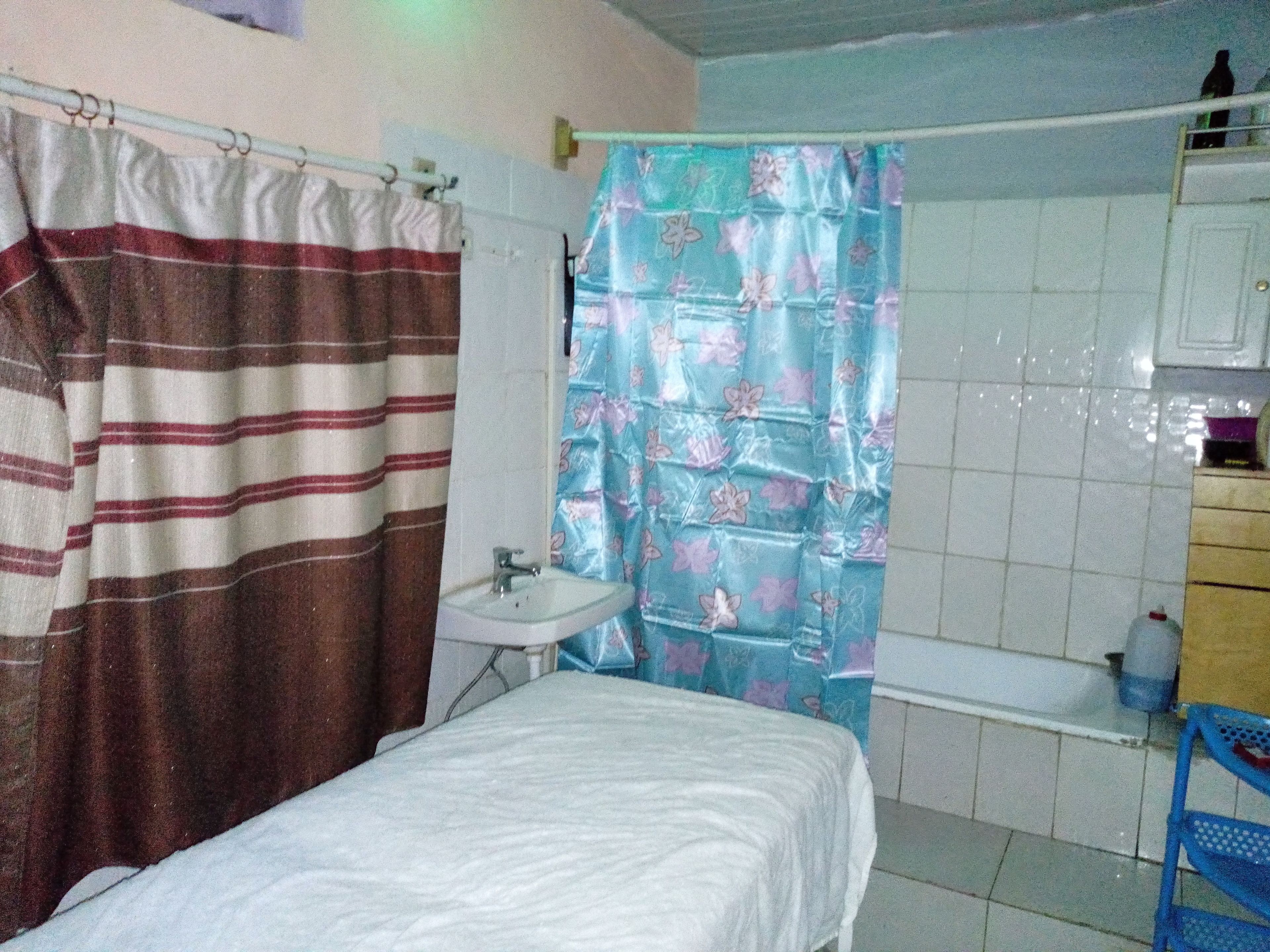 Ein kleines, schlichtes Badezimmer mit Bett, Waschbecken und Duschvorhang.