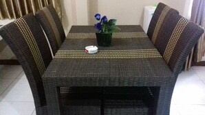 A dining table with four chairs, a potted plant, and a white ashtray. - Kota Bunga R (Cipanas)