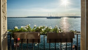 Ein Balkon mit Blick auf das Meer, ein Schiff in der Ferne und eine strahlende Sonne.