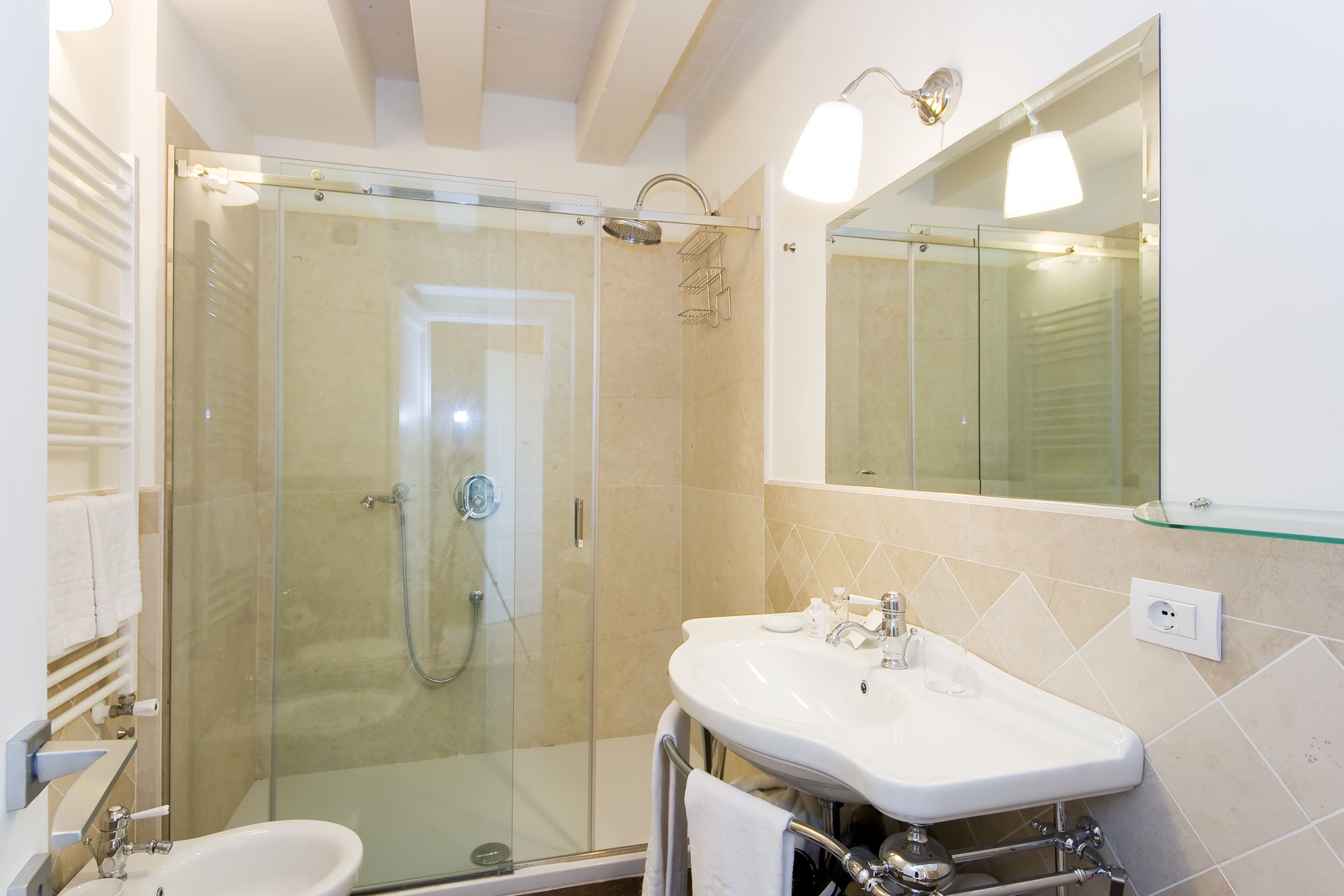 Une salle de bain moderne avec une douche à parois de verre, un lavabo blanc et un grand miroir.