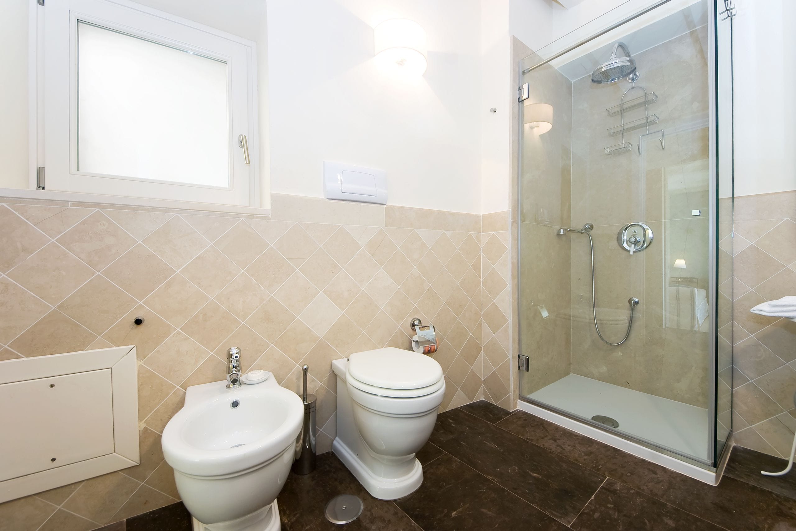 A bathroom with a glass-enclosed shower, a bidet, and a toilet.