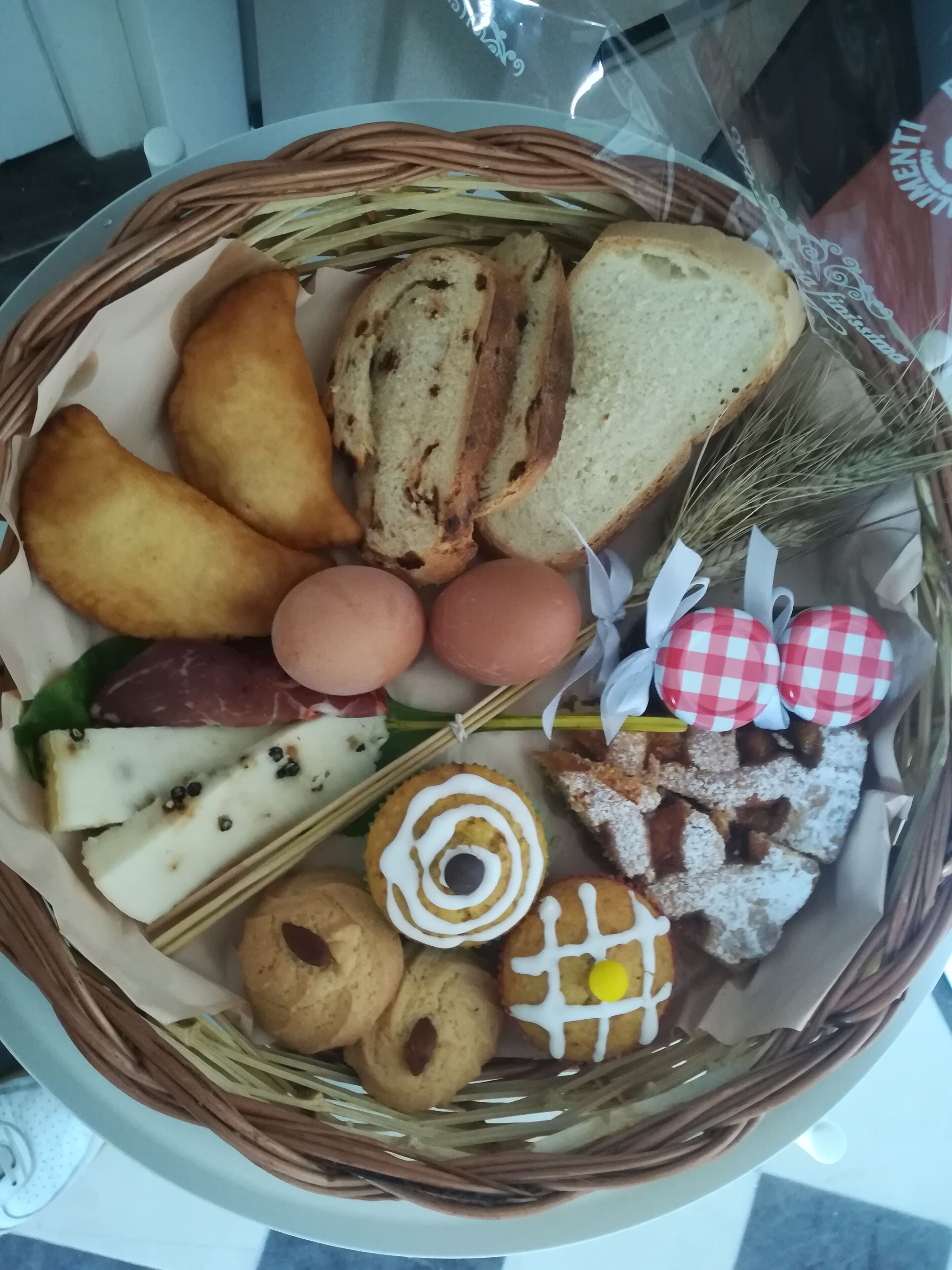 Een mand gevuld met diverse lekkernijen, zoals brood, koekjes en gebak.