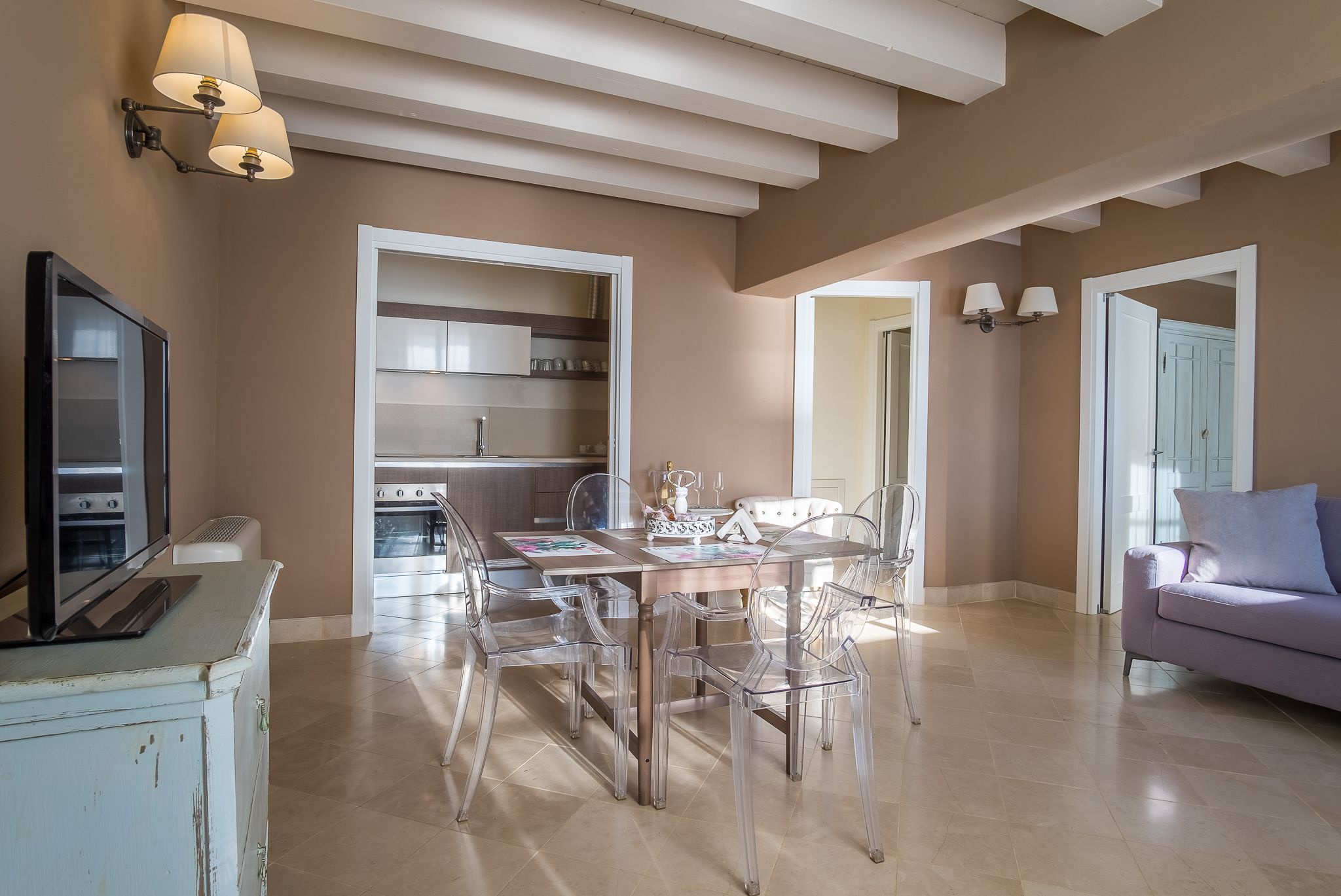 A spacious living area with a dining table and chairs, a sofa, and a television on a cabinet.