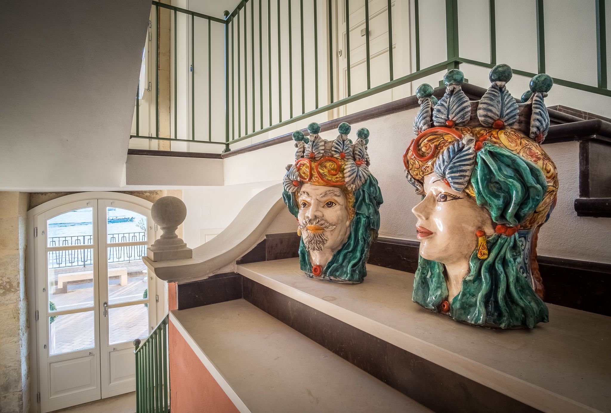 A staircase with a railing and a decorative headpiece on the wall.