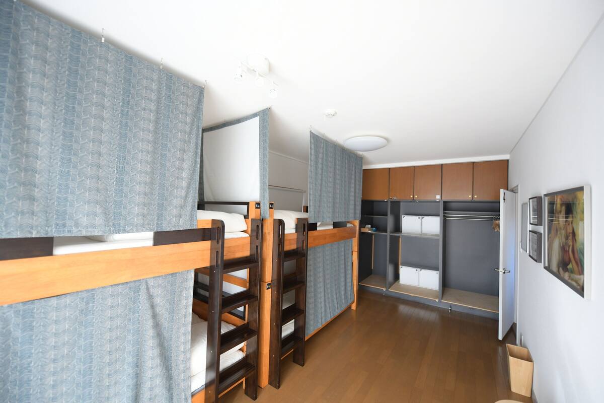 A compact room with bunk beds, a kitchenette, and a small bathroom.