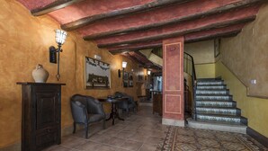 A lobby with a tiled floor, a staircase, and a wall-mounted light fixture. - Casa Rural La Cuca (Lerín)