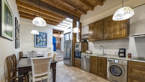 A modern kitchen with wooden cabinets, stainless steel appliances, and a dining area with a table and chairs. - Casa Rural La Cuca (Lerín)