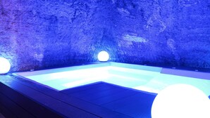 A spa area with a blue-lit wall and a rectangular hot tub. - Casa Rural La Cuca (Lerín)
