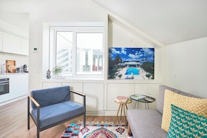 A modern living room with a sofa, a blue chair, a small table with a book and glasses, and a colorful rug. - Lisbon Best Choice Prime Apartments Alfama (Lisbon)