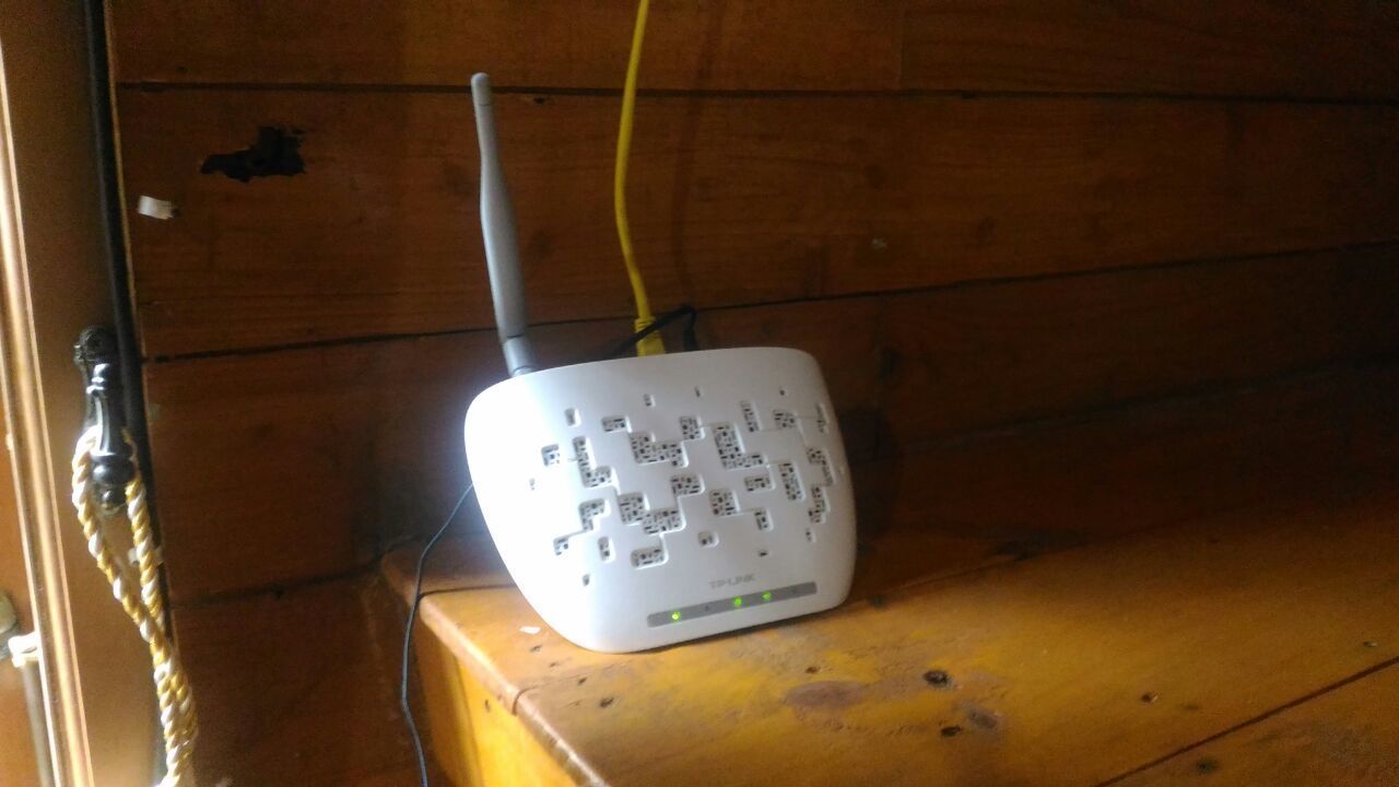 Un dispositivo electrónico blanco con varios puertos y un cable amarillo sobre una superficie de madera.