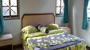 A bedroom with a bed, nightstands, and curtains. - Kota Bunga Q (Cipanas)