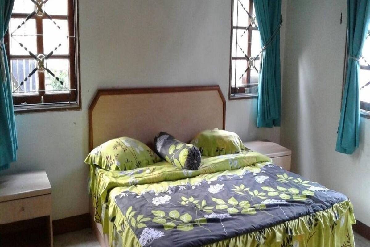 A bedroom with a bed, nightstands, and curtains.