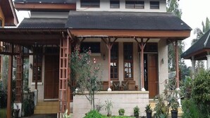 A two-story house with a covered porch and a small garden. - Kota Bunga Q (Cipanas)