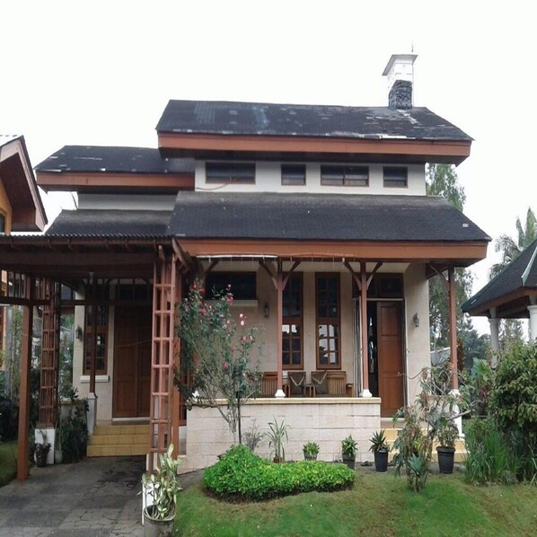A two-story house with a covered porch and a small garden. - Kota Bunga Q (Cipanas)